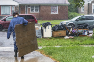 Michigan Program Extended- volunteer carries a section of damaged wall to a pile on the curb